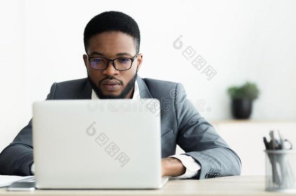 集中的非洲的美国人家伙工作的向便携式电脑采用办公室