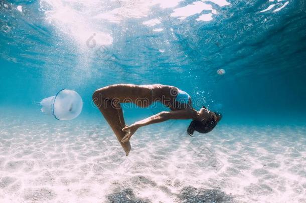 女人潜水员滑行越过沙的海和水母.自由生活采用