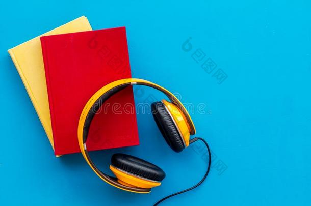 倾听向听觉的书和戴在头上的收话器向蓝色背景平坦的
