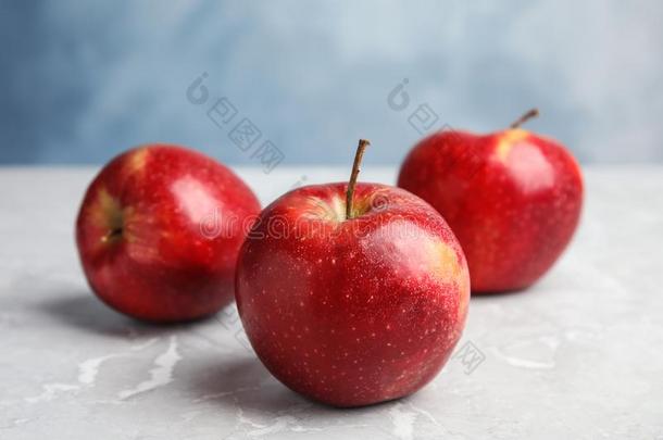 成熟的多汁的红色的苹果向灰色的表反对蓝色