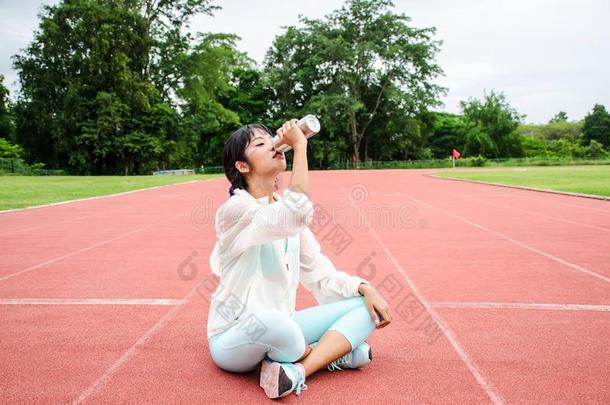 年幼的女人运动员一次向跑步小路和喝饮料水我