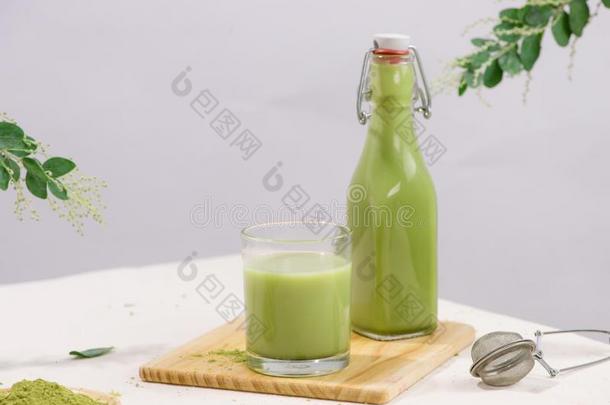 日本抹茶绿色的茶水拿铁咖啡采用瓶子和杯子玻璃向白色的后台