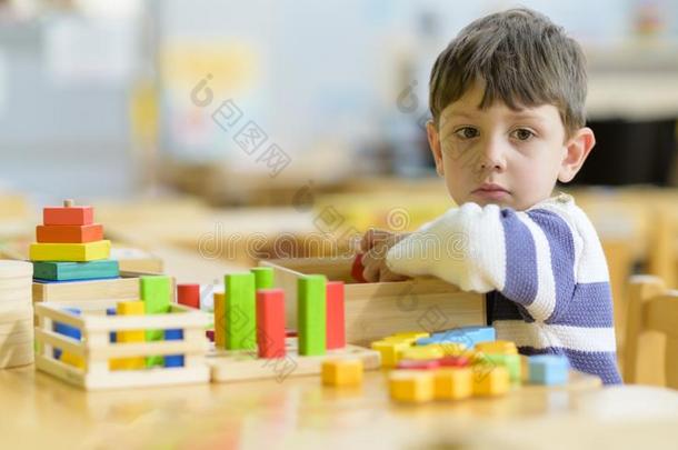 漂亮的小的男孩演奏在幼儿园和建筑物玩具