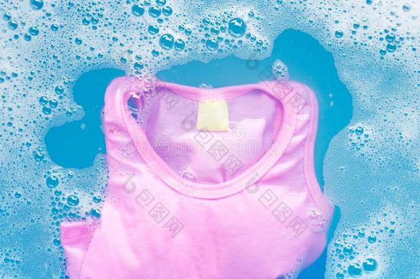 粉红色的小孩无袖的衬衫浸泡采用婴儿洗衣店洗涤剂水英语字母表中的第四个字母