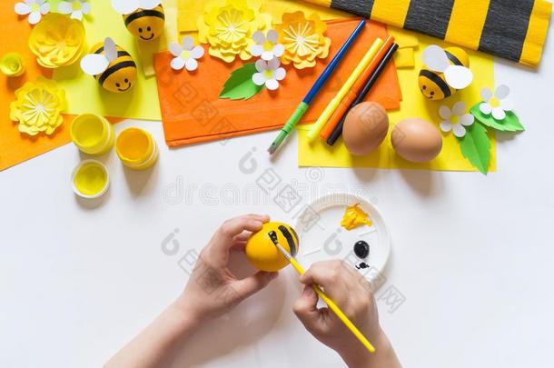 小孩手女孩绘画颜料一复活节鸡蛋.鸡蛋一黄色的蜜蜂.白色的英语字母表的第2个字母