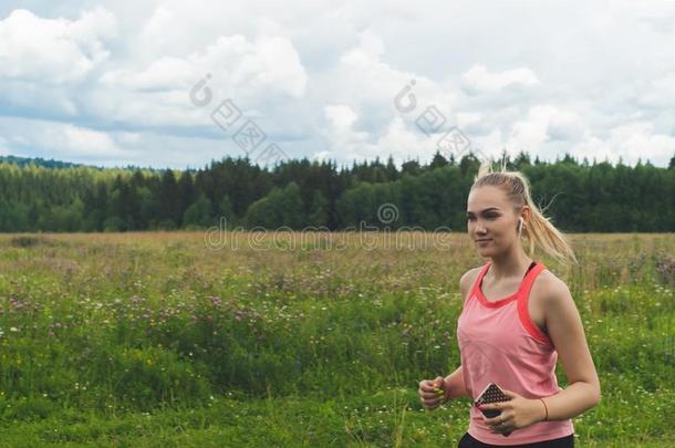 年幼的女人慢跑采用指已提到的人草地和listen采用g向音乐向上端