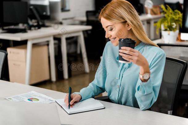 微笑的女商人和咖啡豆向走制造记下采用笔记簿
