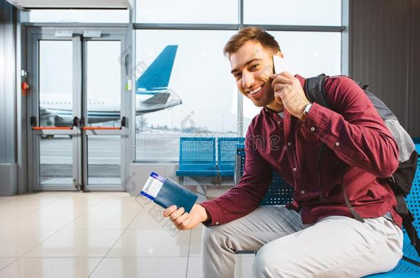微笑的男人讲话向smartph向e在期间一次采用机场