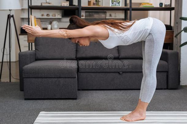 年幼的女人开业的瑜伽使摆姿势在家采用
