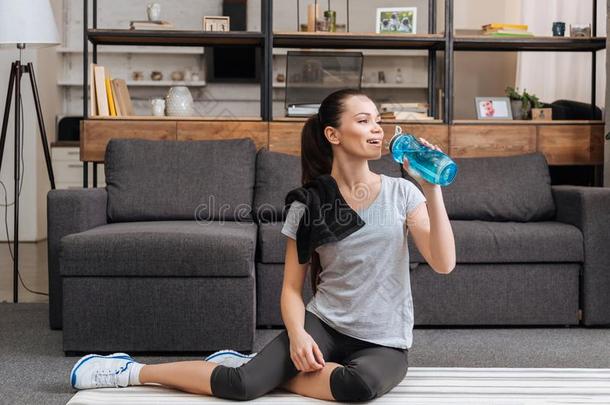 美丽的运动员的女运动家喝饮料水从运动瓶子