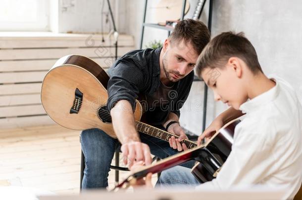 两个兄弟演奏吉他.年长的兄弟教年纪较小者num.一向
