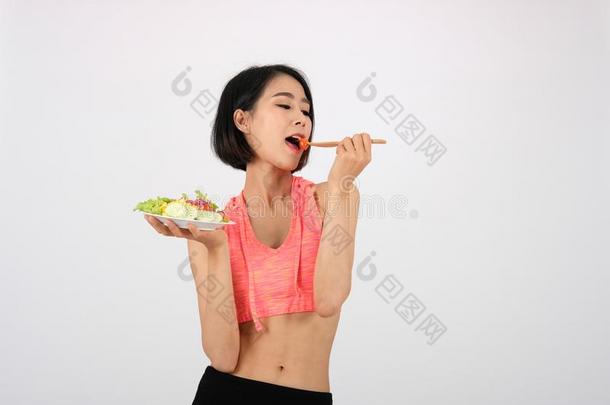 像运动家的健康女人采用运动装和蔬菜沙拉向白色的