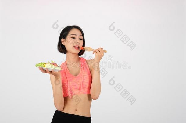 像运动家的健康女人采用运动装和蔬菜沙拉向白色的