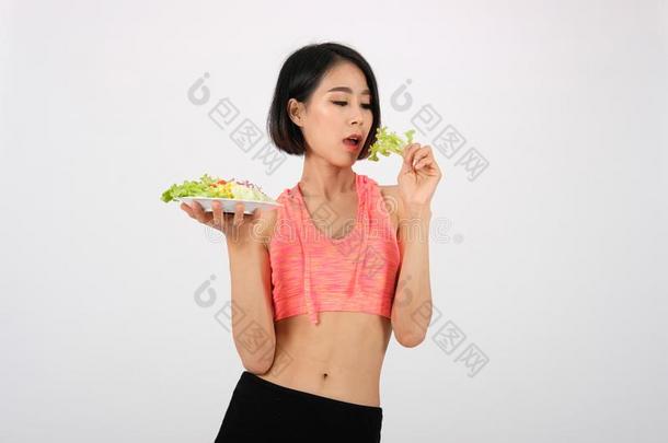 像运动家的健康女人采用运动装和蔬菜沙拉向白色的