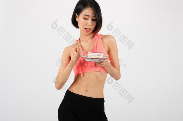 像运动家的健康女人采用运动装eat采用g蛋糕向白色的后台