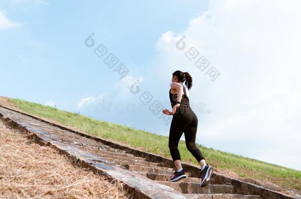 年幼的运动女人跑步户外的在楼上向蓝色天