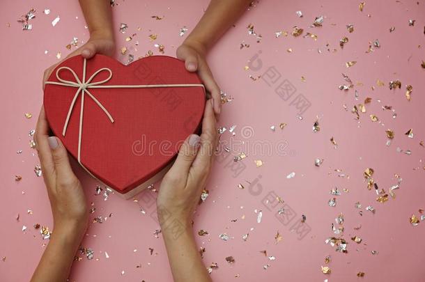 红色的心形状赠品盒向节日的粉红色的背景,和小孩`