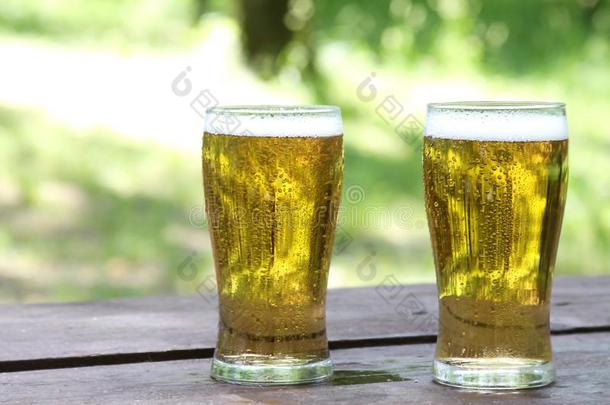 两个眼镜关于<strong>金色</strong>的寒冷的啤酒向木制的表,<strong>户外</strong>的.和英语字母表的第3个字母