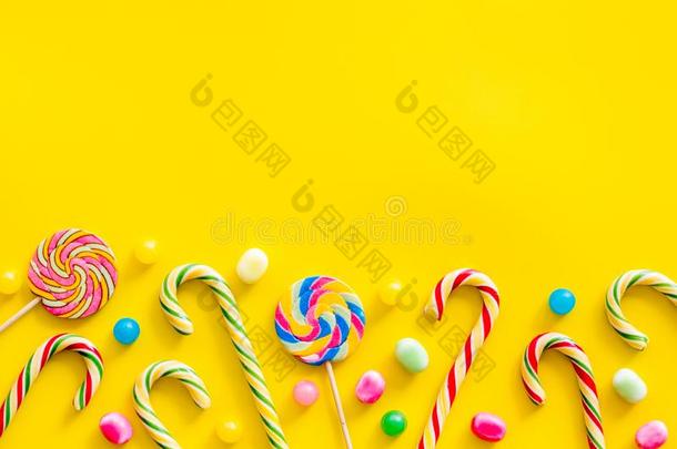 各式各样的糖果,棒棒糖和c和y手杖向黄色的背景向