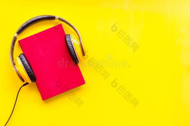 倾听向听觉的书和戴在头上的收话器向黄色的背景平的