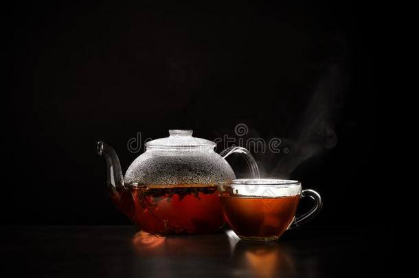 玻璃茶壶和杯子关于热的茶水向表黑的背景,土壤-植物-大气连续体