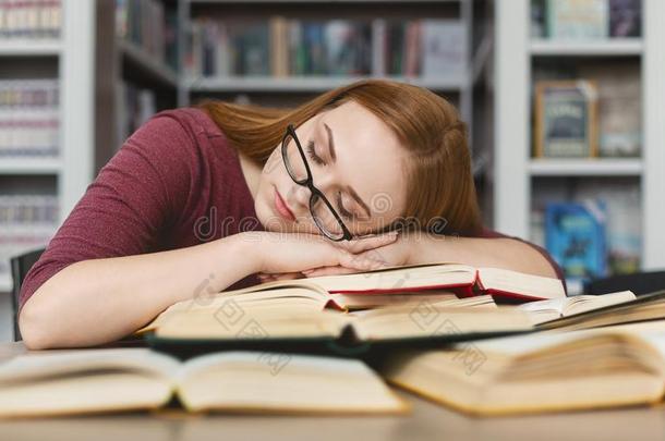疲倦的女孩和眼镜所有小睡向书采用图书馆