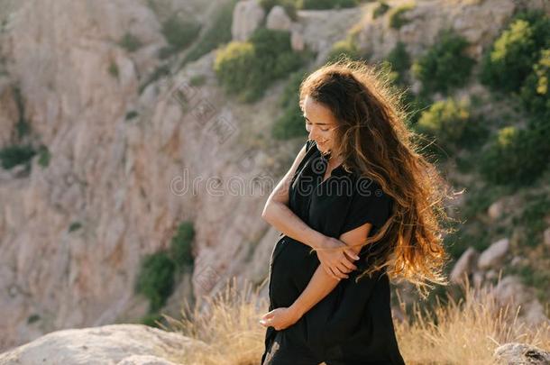 幸福的怀孕的女人和长的头发向顶关于山.