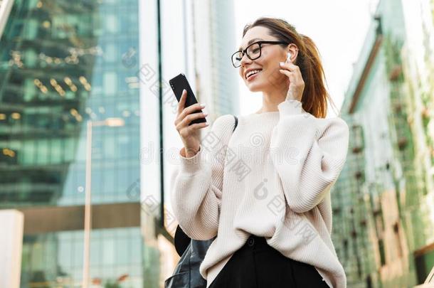 照片关于有魅力的微笑的女人使用蜂窝式便携无线电话和耳朵whiteiron白铁