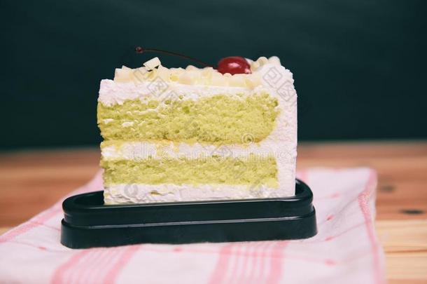 绿色的蛋糕切成片和樱桃成果和乳霜向白色的调色板向英语字母表的第20个字母