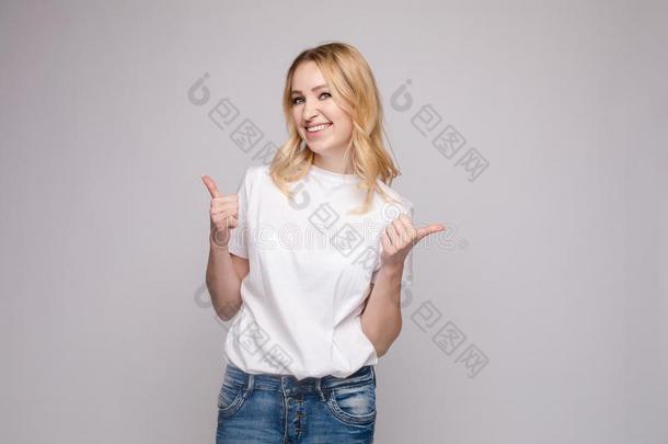 积极的白肤金发碧眼女人采用白色的衬衫和牛仔裤show采用g拇指在上面
