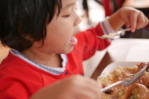 小的亚洲人婴儿女孩吃白色的稻和猪肉和鸡蛋斯图尔特
