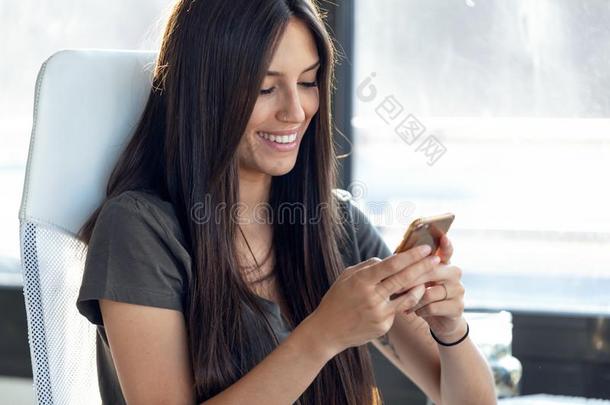 微笑的年幼的商业女人发送信息和可移动的电话