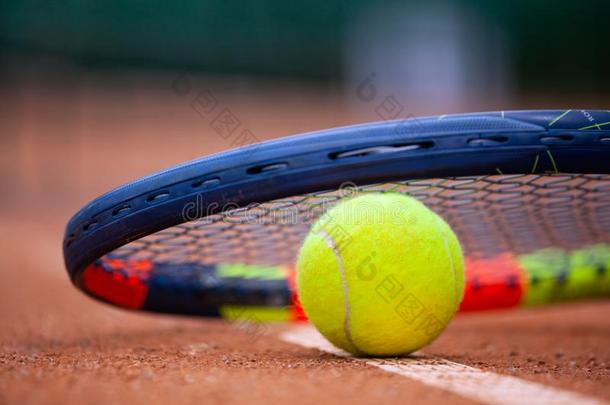 黄色的网球球和球拍躺向指已提到的人黏土法院