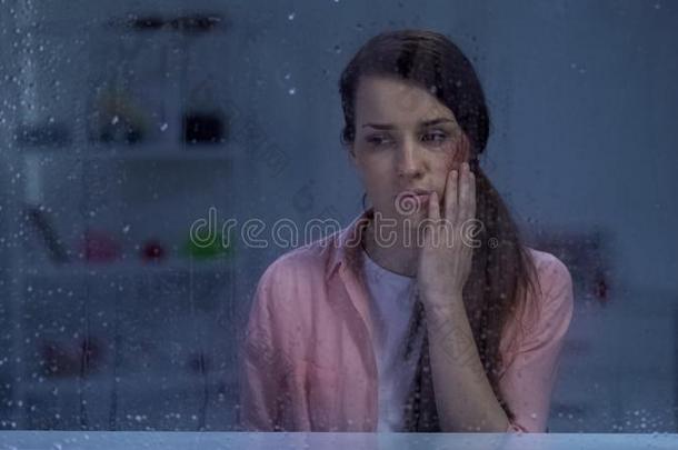 情绪低落的女人和负伤的面容一次在的后面下雨的窗,一