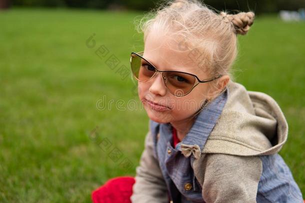 一女孩采用对光反应变色的眼镜向一绿色的田,一严肃的看
