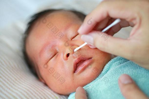 关在上面母亲使用棉芽向干净的婴儿眼睛