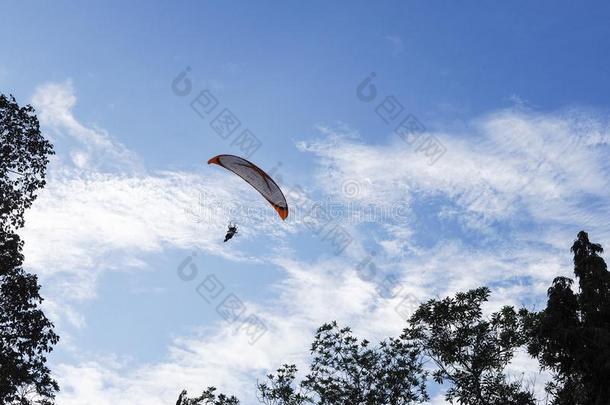 一男人飞行的采用指已提到的人美丽的蓝色多云的天,降落伞和一
