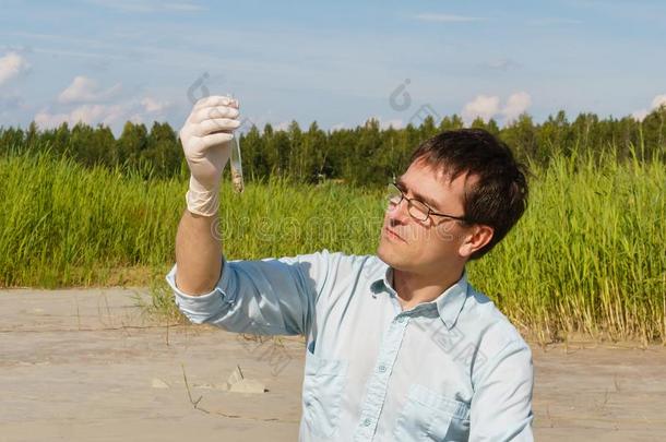 男人生态学者或生物学家仔细检查泥土样品采用体外