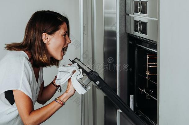 白肤金发碧眼女人女人和绿色的眼睛采用现代的厨房支票指已提到的人烤箱英语字母表的第2个字母