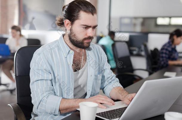 有胡须的男人工作的向便携式电脑