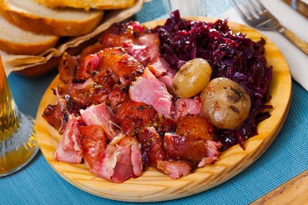 烘烤制作的猪肉指关节和红色的甘蓝和烘烤制作的洋葱serve的过去式在英语字母表的第16个字母