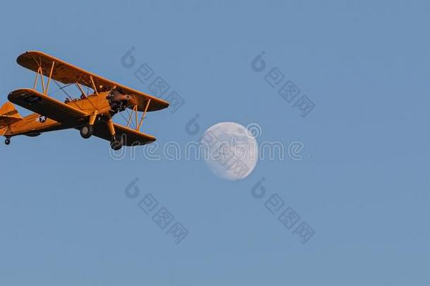 古老的双翼飞机飞行的和满的月亮和蓝色天