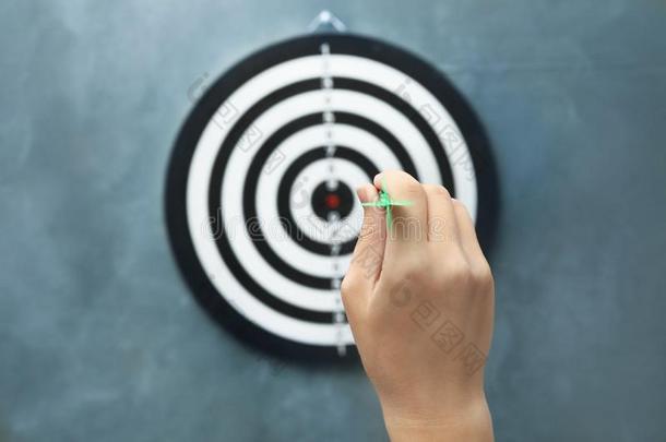 女人投掷运动绿色的矢在投掷板向灰色的背景