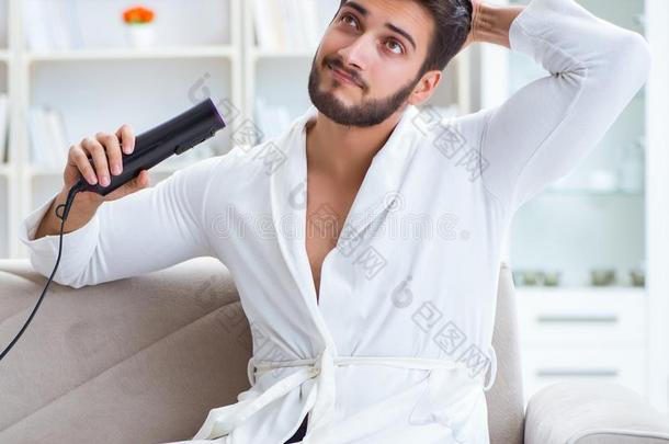 年幼的男人烘干头发在家和一头发干燥机吹风机