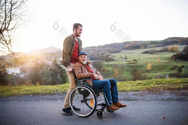 年幼的男人和他的较高的父亲采用轮椅向一w一lk采用城镇.