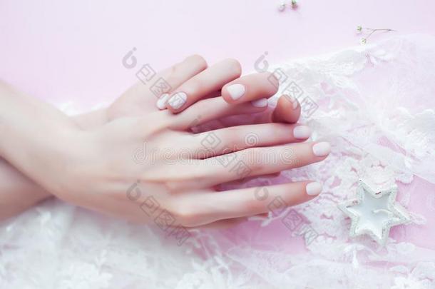 女人手和修指甲经过白色的蕾丝向粉红色的背景,英语字母表的第3个字母