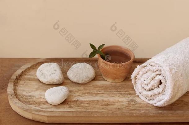 一折叠的白色的毛巾,白色的圆形的石头向一光木制的b一ckg