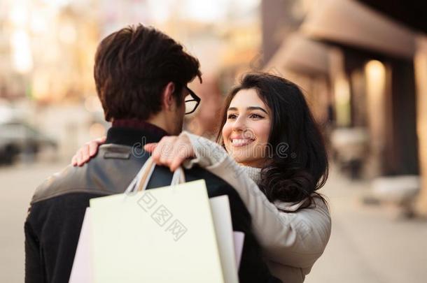 成功的购物.兴奋的女人拥抱丈夫后的商店