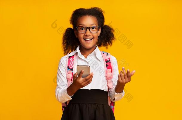 幸福的非洲的美国人女学生吃草向蜂窝式便携无线电话,黄色的