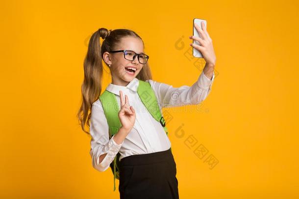 女学生使用智能手机迷人的自<strong>拍照</strong>做<strong>手势</strong>英语字母表的第22个字母-符号,叫喊